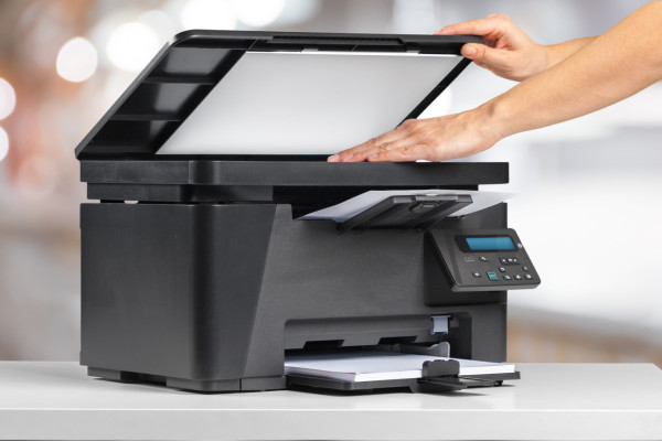 Oseba, ki naloži izpis na površino za skeniranje večfunkcijskega tiskalnika.